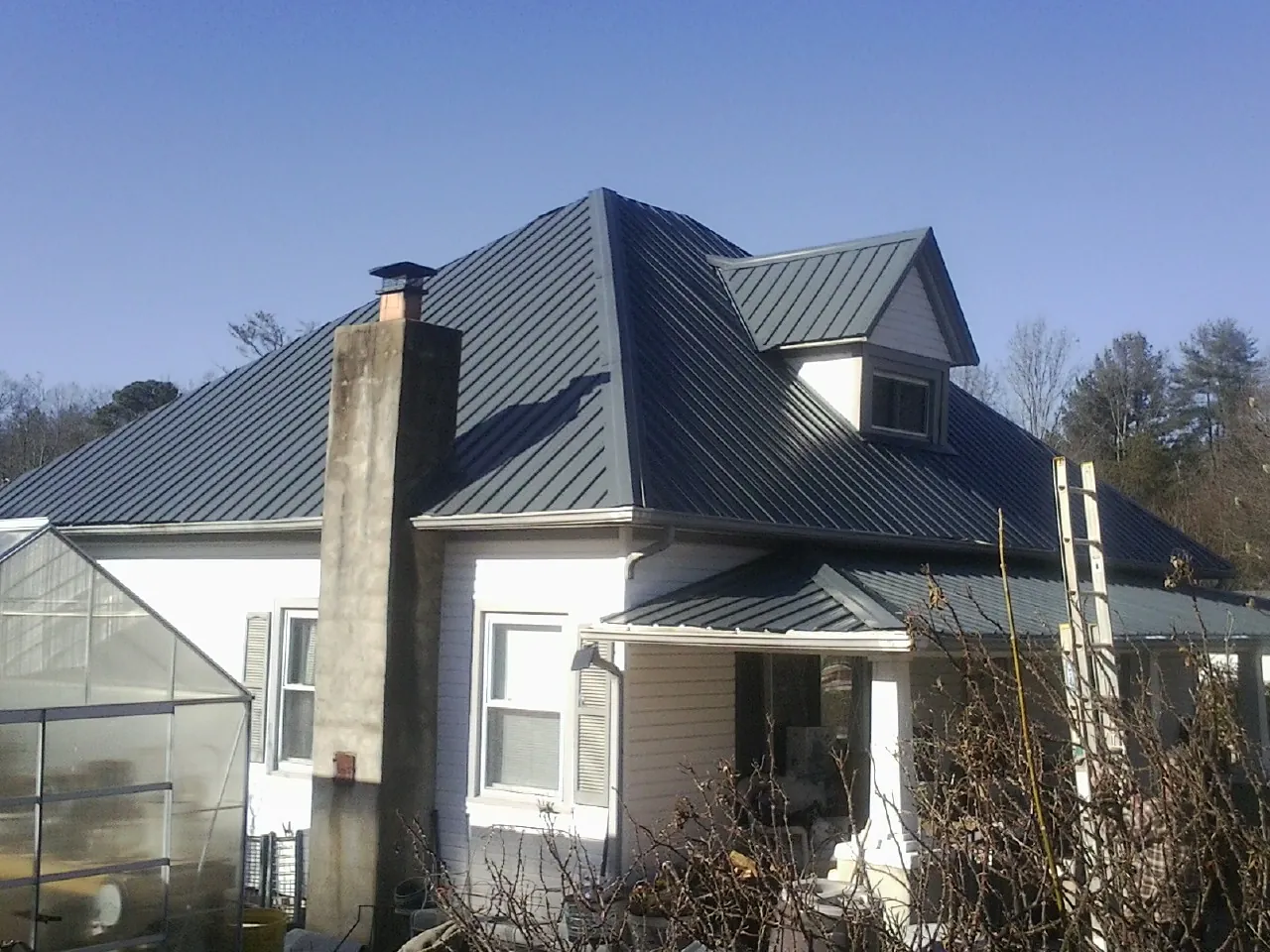 Dark blue standing seam metal roof on a white farmhouse with dormer — Slate & Tile Roof Repair by Roofing Brothers in White House