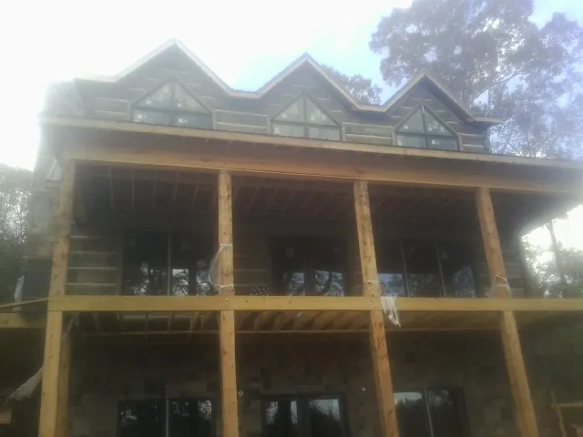 Dormers and porch framing on a large log home under construction — Roof Coating work by our crew in White House