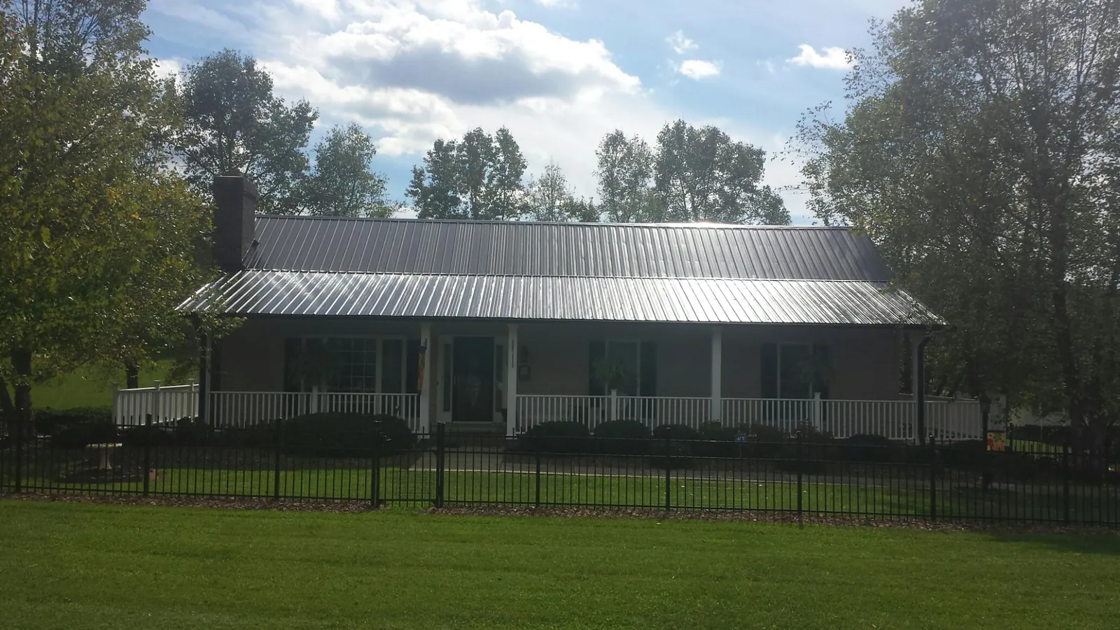 Gray metal roof on a brick ranch with a full width front porch — Gutter Guard Installation work by our crew in White House