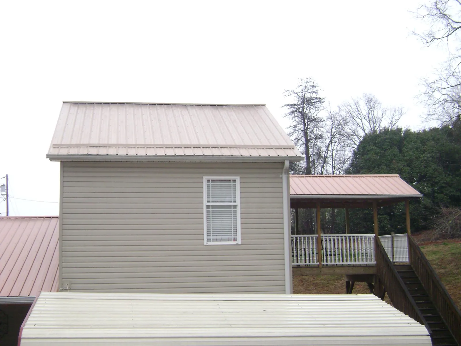 Tan metal roofs on a two story addition and attached porch, from a Roof Replacement job in White House