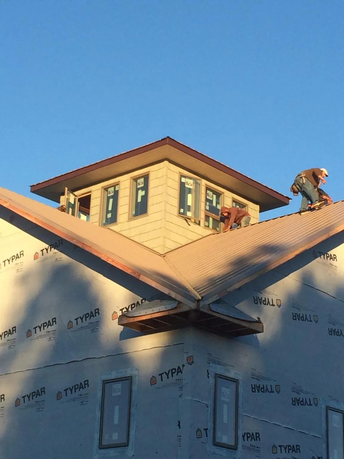Roofers working around a rooftop cupola on a new metal roof at sunset — Roof Waterproofing in White House by Roofing Brothers